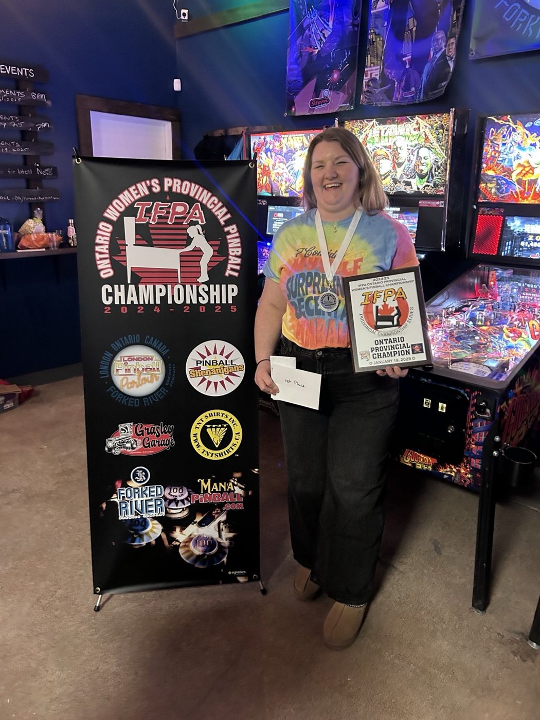 The 2024-25 Ontario women's provincial champion holding her plaque beside the championship banner